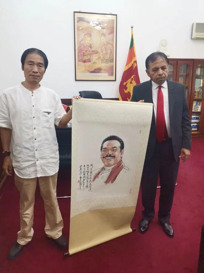 Li Shiliang handing his portraits of the former president to Ambassador Palitha Kohona for delivery